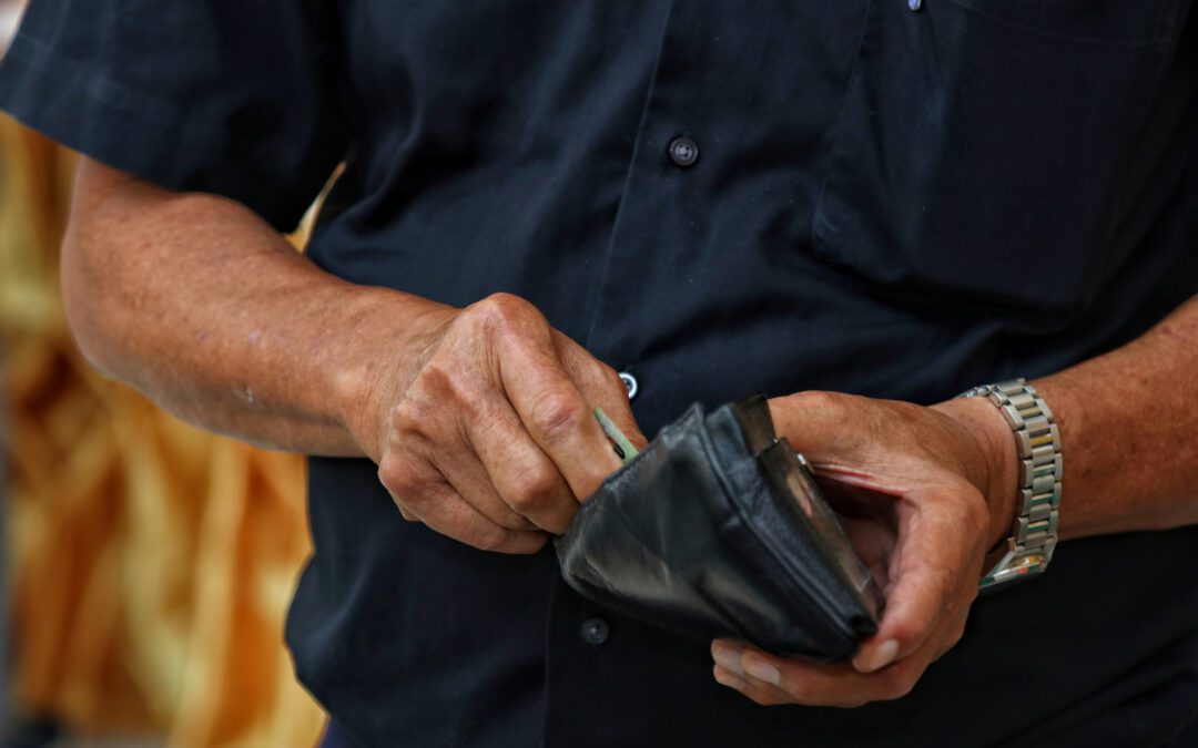 Gentleman pullng money out of his wallet as he considers financial steps to take before the end of the year