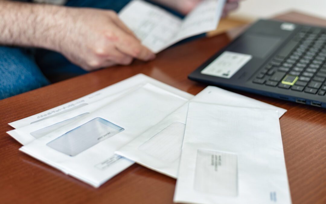 Man opening tax documents that came in the mail next to laptop