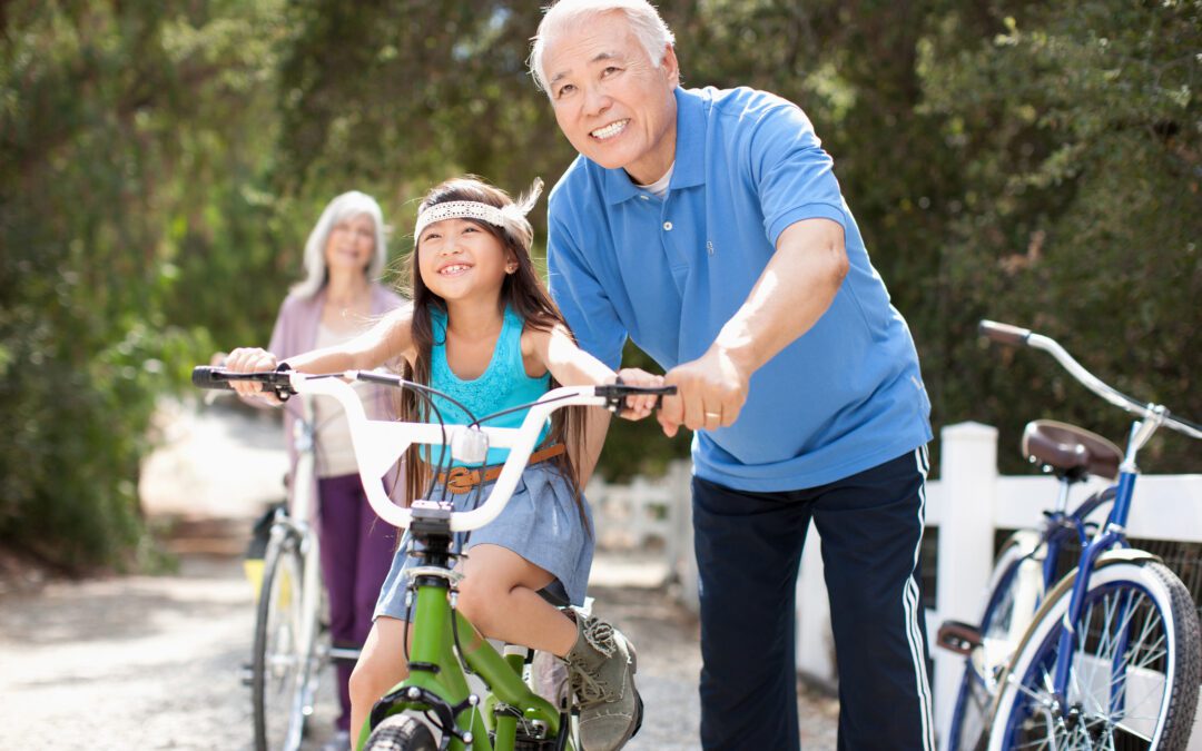 Grandfather helping grandaughter ride bike while contemplating how to help her achieve future financial success