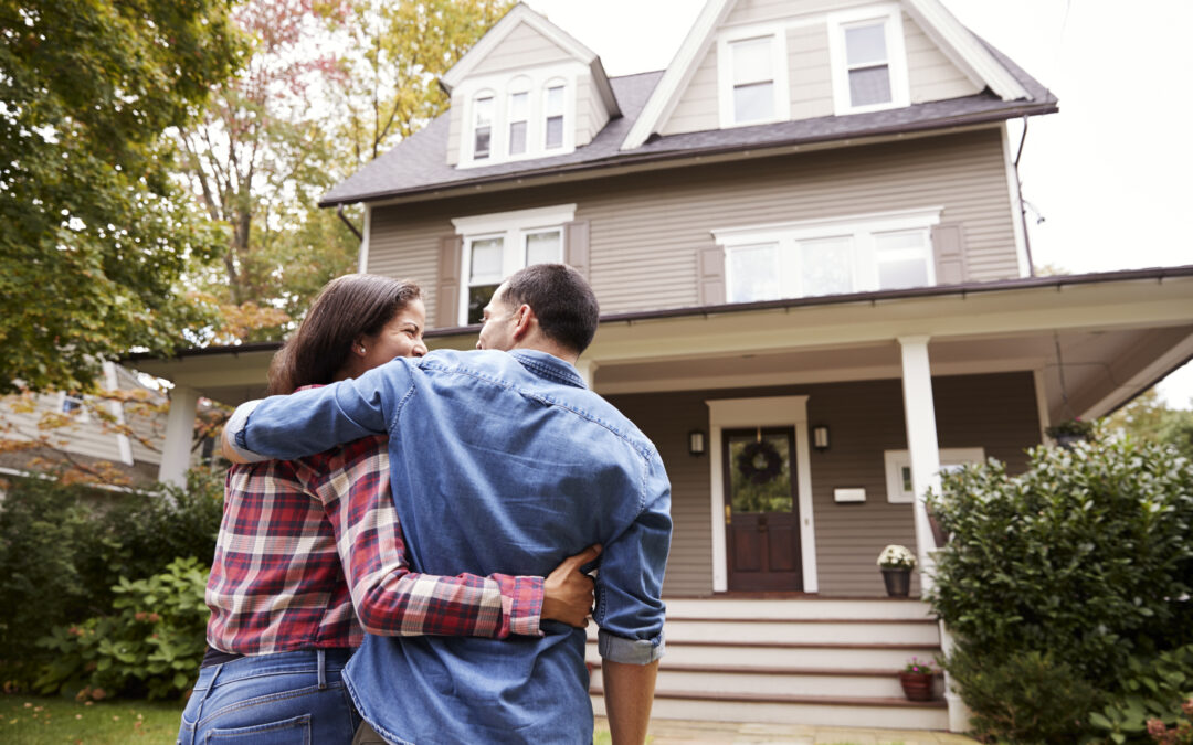 Couple considering paying off mortgage early as they stand in front of house looking at it