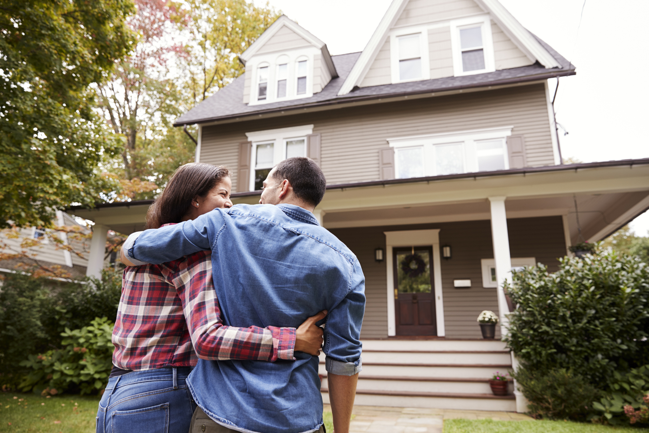 Couple considering paying off mortgage early as they stand in front of house looking at it